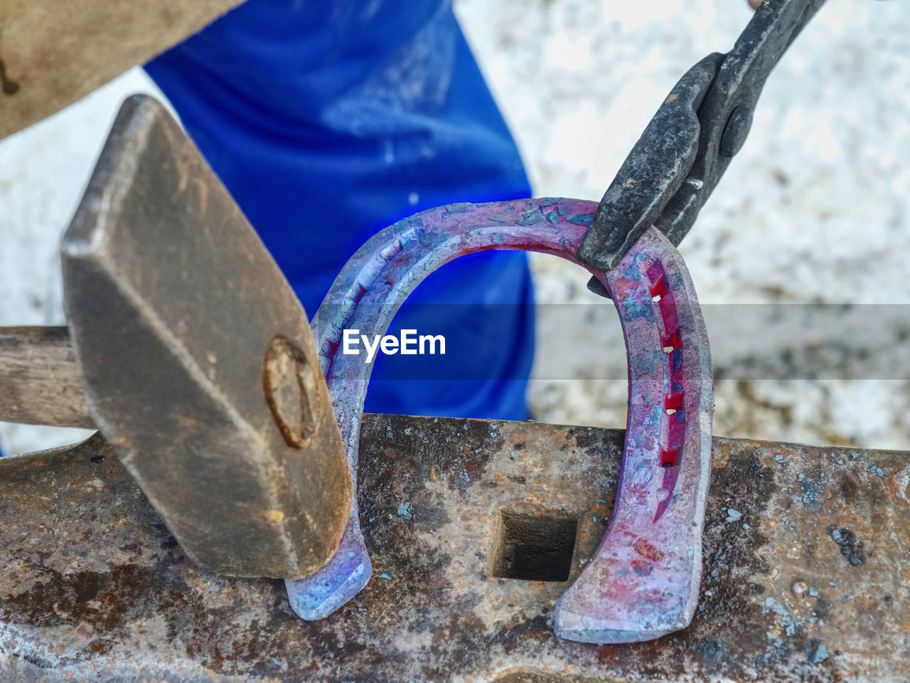 Detail of making new horseshoe in blacksmith workshop. male farrier hammers a nail into a horseshoe