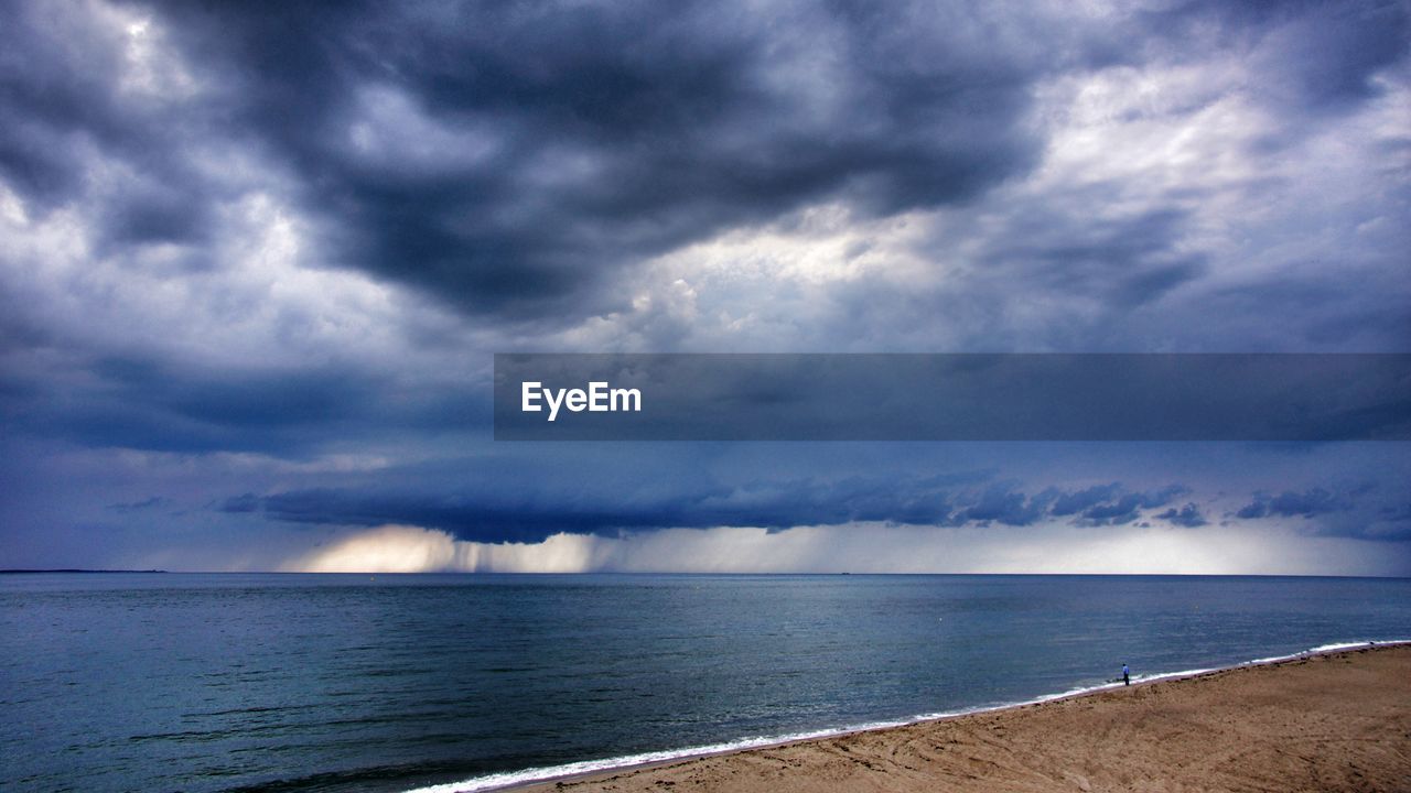 Scenic view of beach and sea against cloudy sky