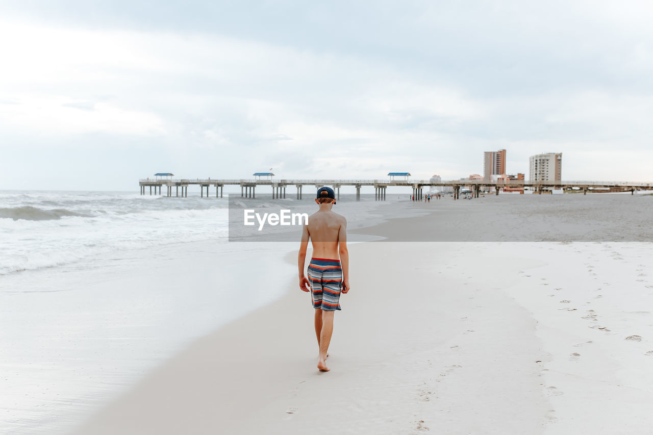 Rear view of teenage boy walking on beach