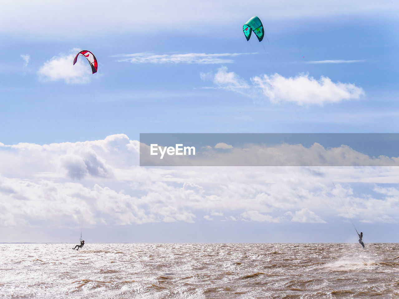 PEOPLE PARAGLIDING AGAINST SEA