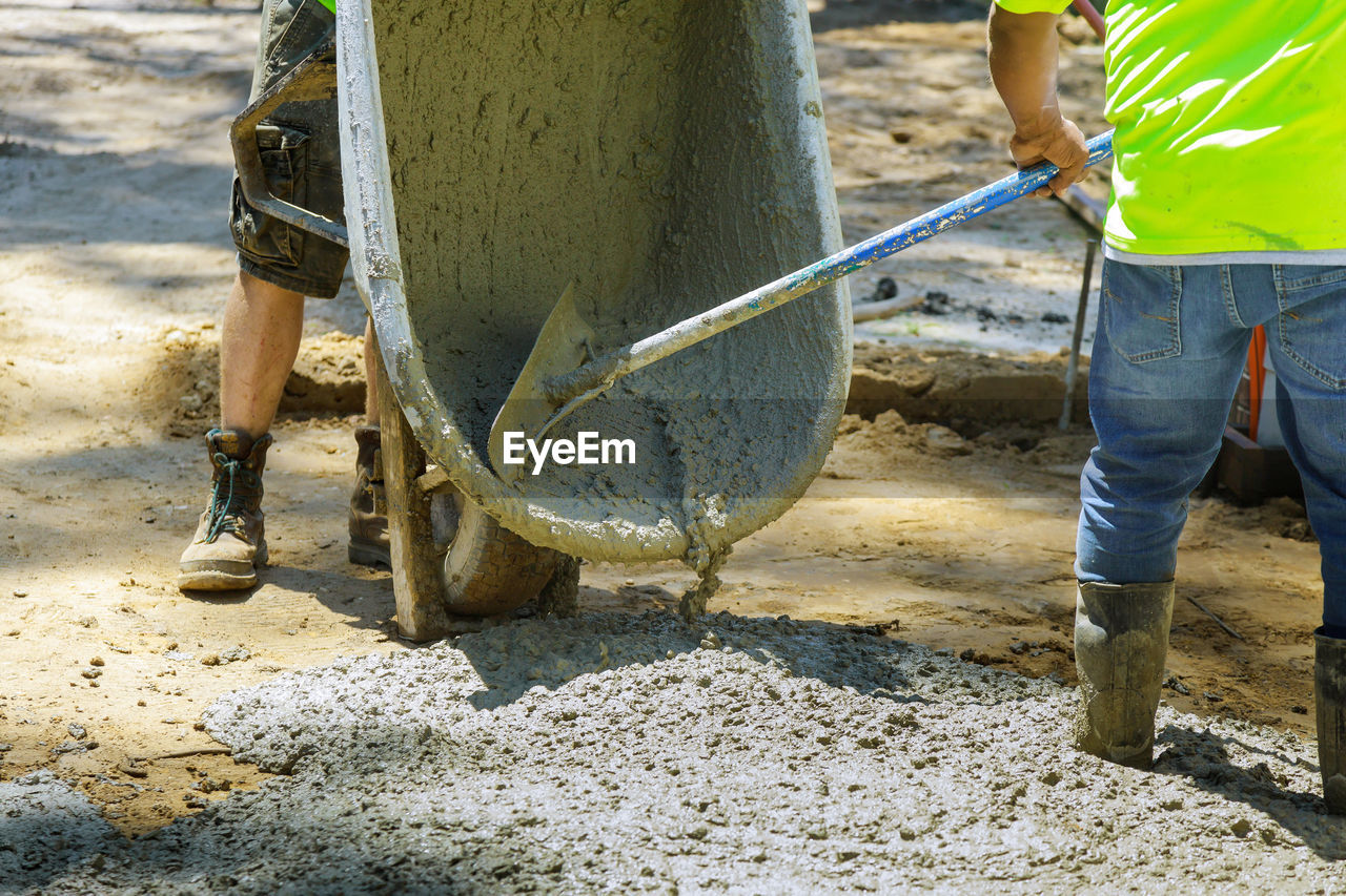 LOW SECTION OF MAN STANDING ON CONSTRUCTION SITE