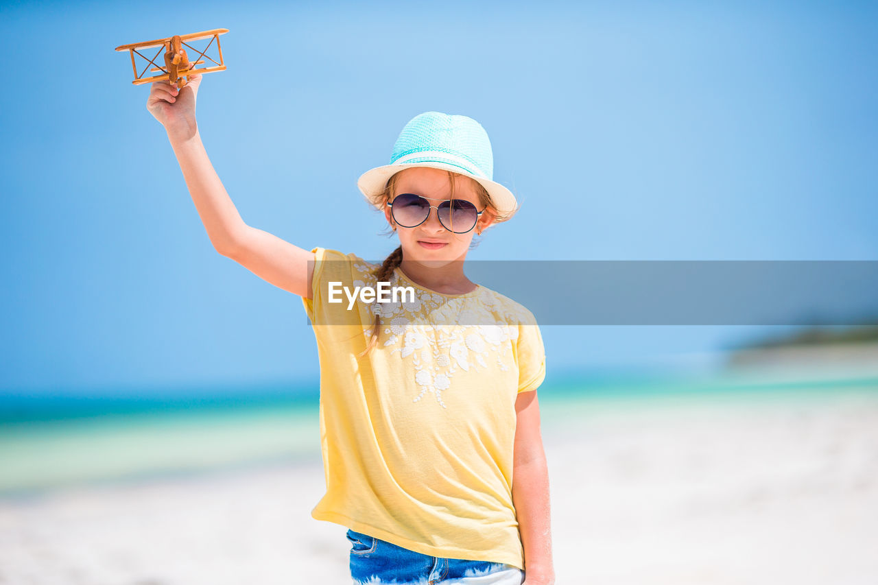 Portrait of girl holding toy airplane at beach