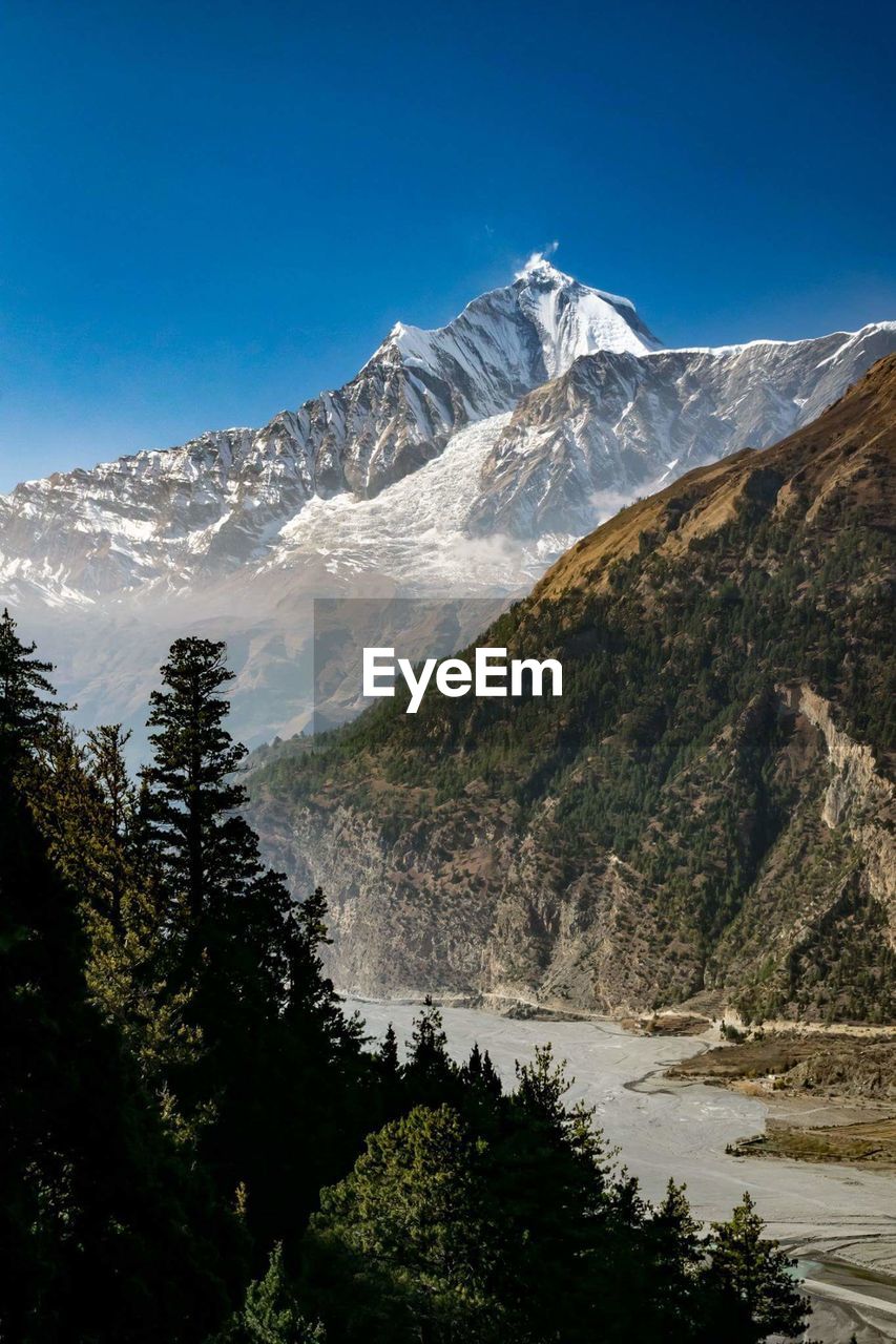 Scenic view of lake and mountains against clear blue sky