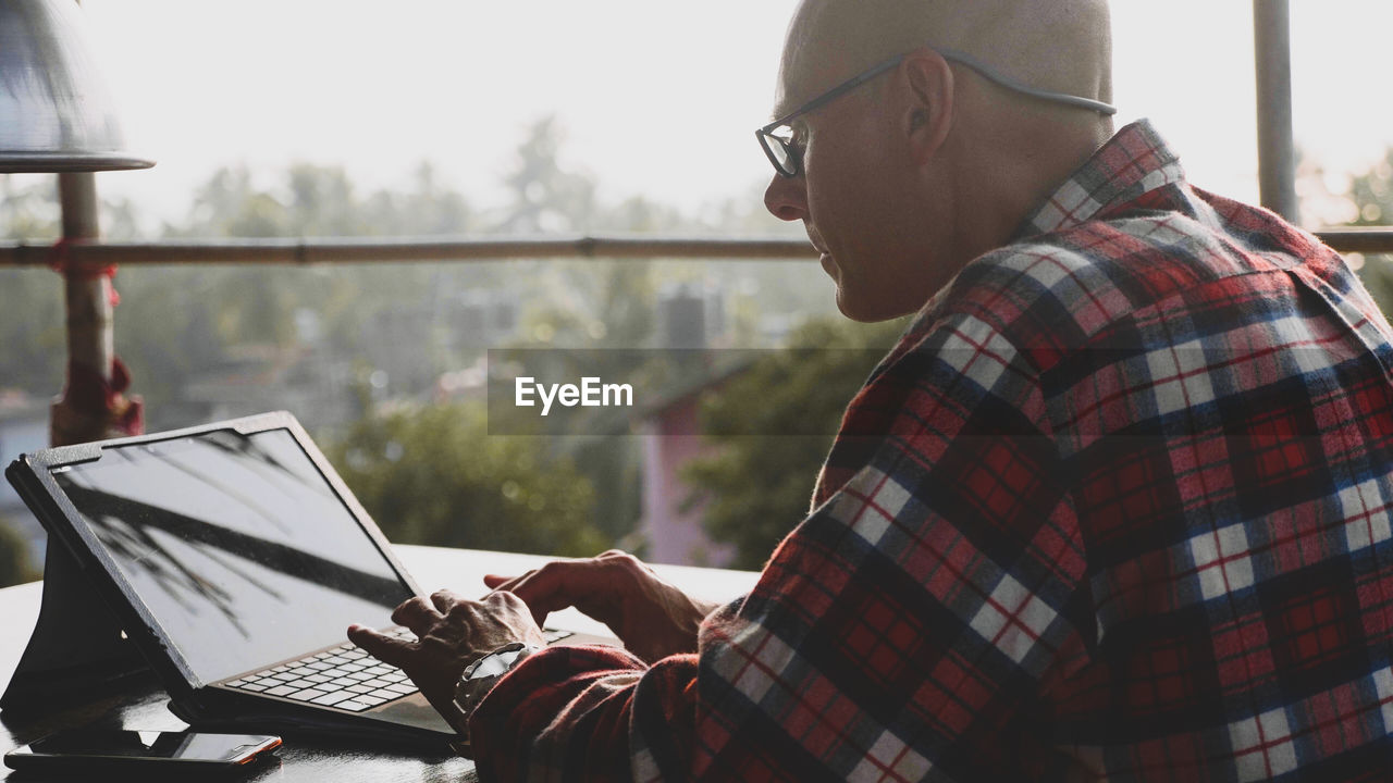 Side view of man using laptop on table