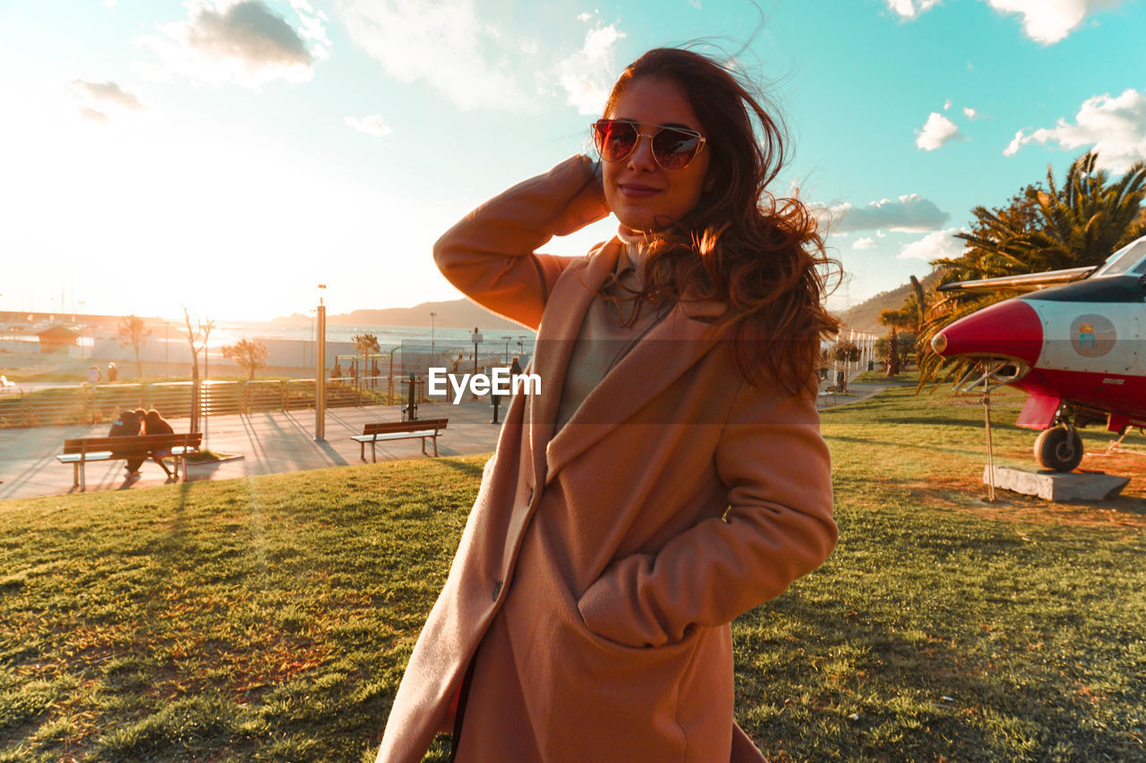 Portrait of woman wearing sunglasses standing on land against sky