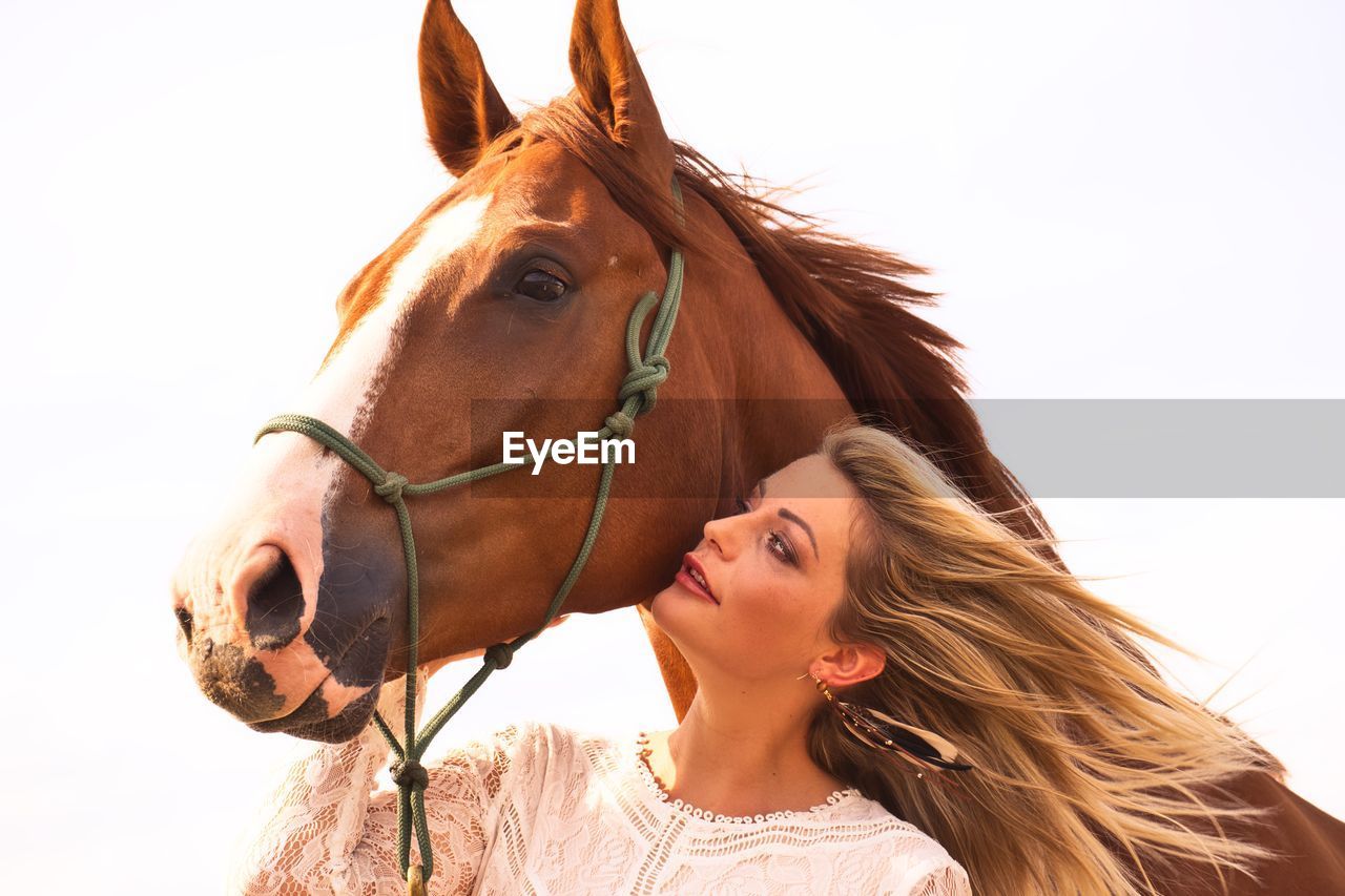 Young woman with horse against clear sky