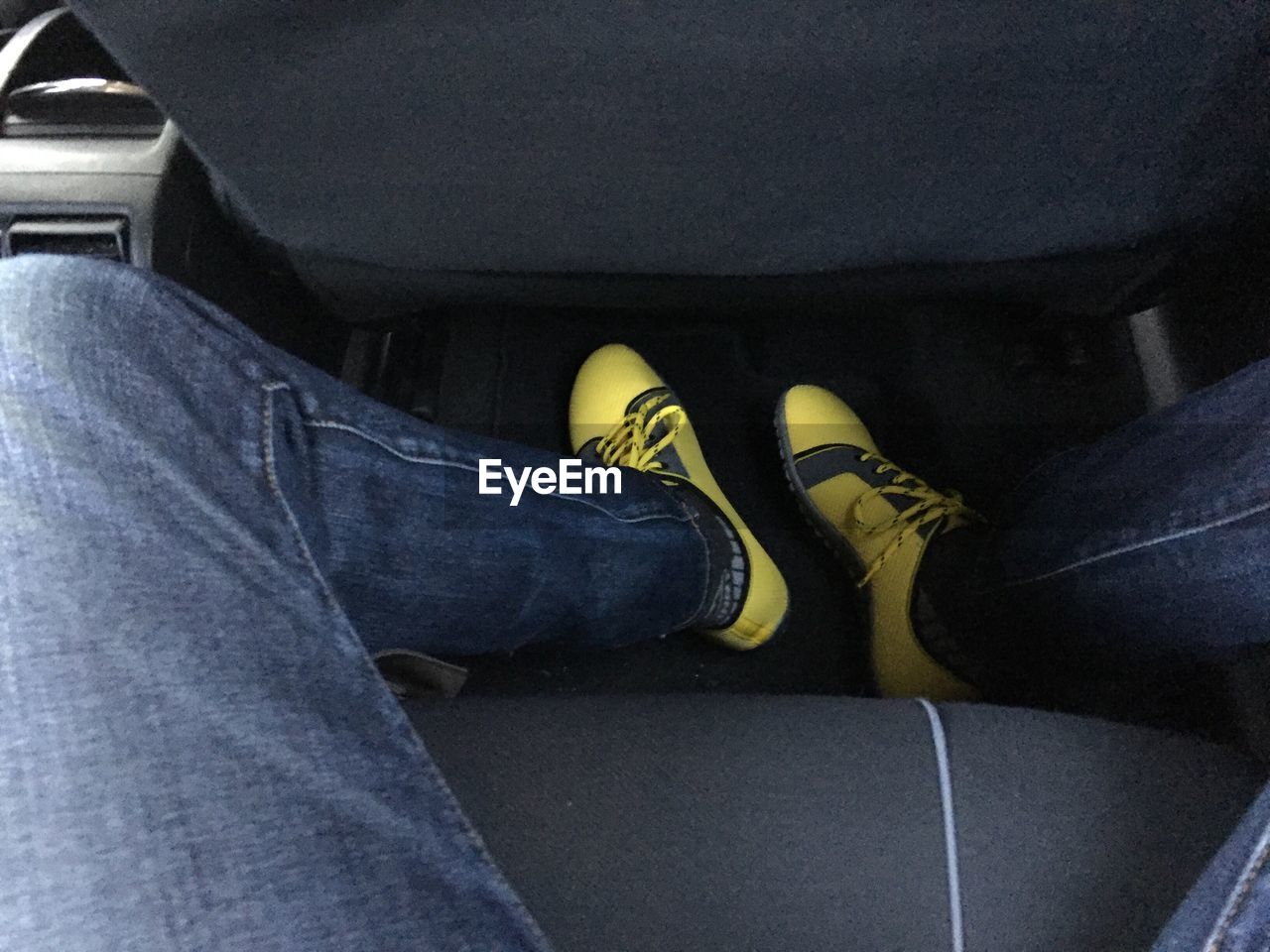 Low section of man wearing yellow shoes sitting in car