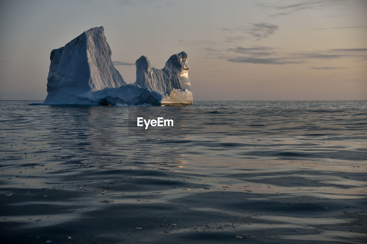 Scenic view of iceberg shapes and reflectins in mirror-like sea in greenland scoresby sound