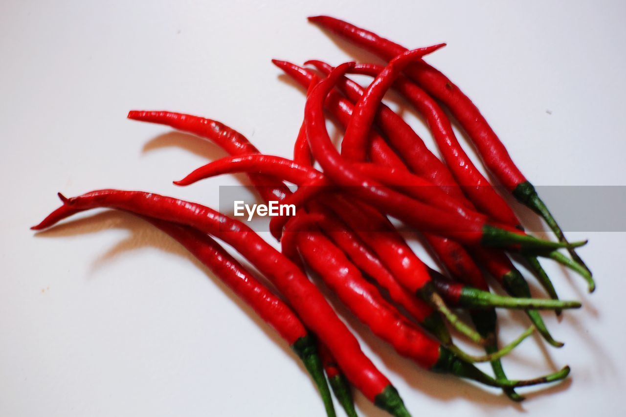 CLOSE-UP OF RED CHILI PEPPERS ON WHITE BACKGROUND