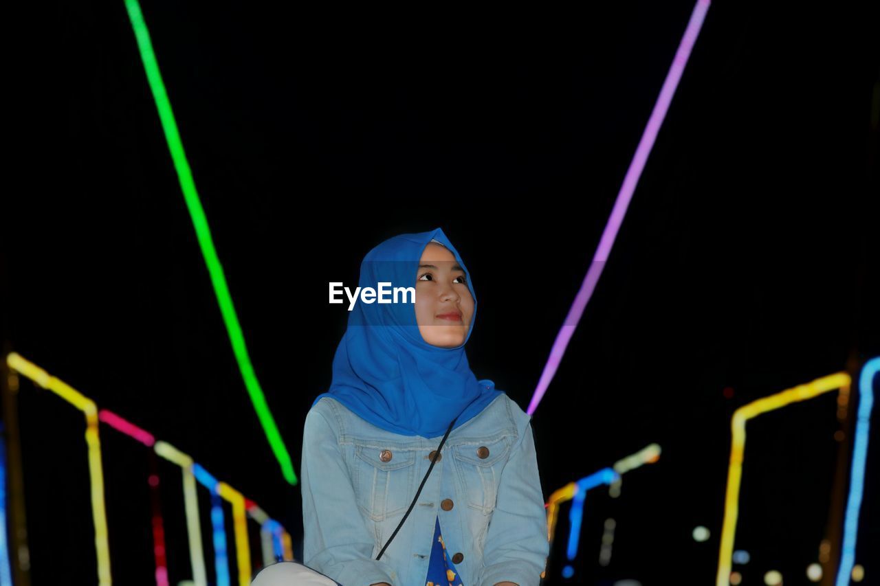 Young woman at amusement park during night