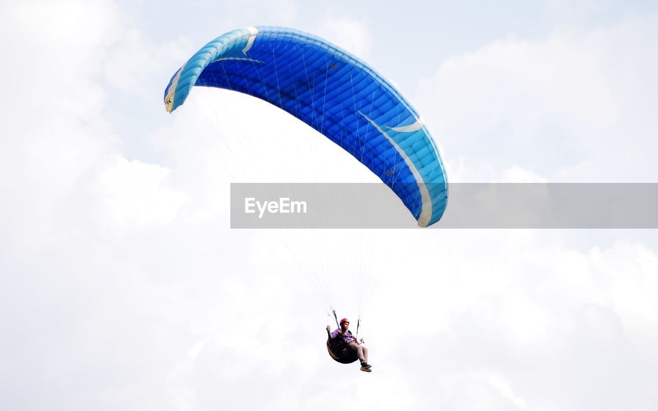 Low angle view of person paragliding against sky