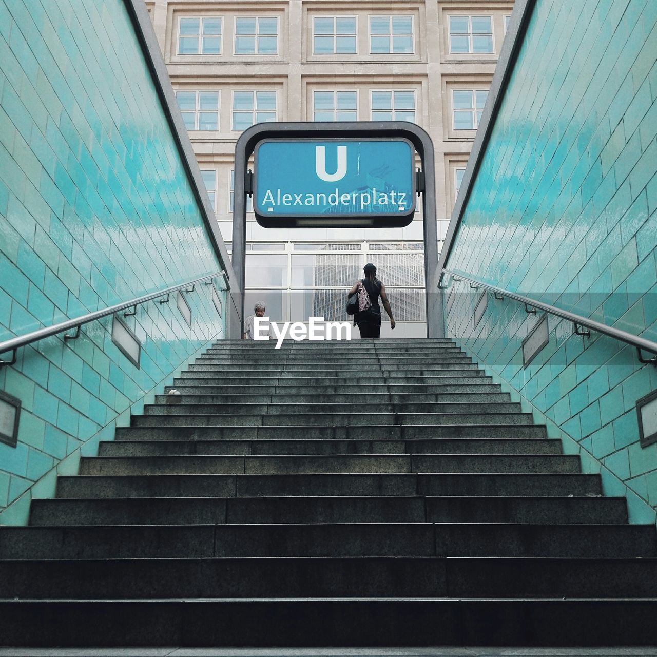 Rear view of woman walking on steps leading towards building at alexanderplatz