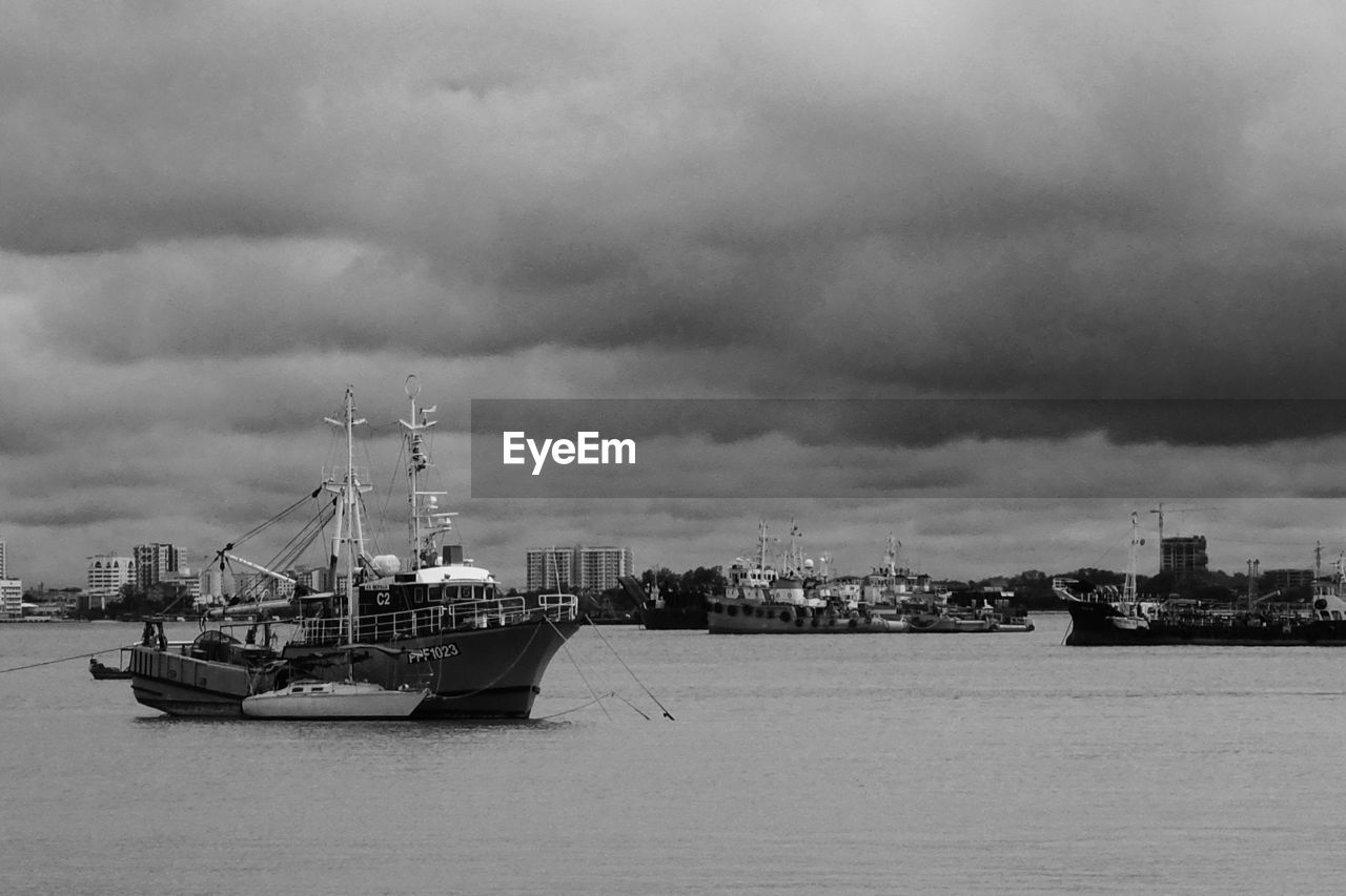 BOATS AT HARBOR AGAINST SKY