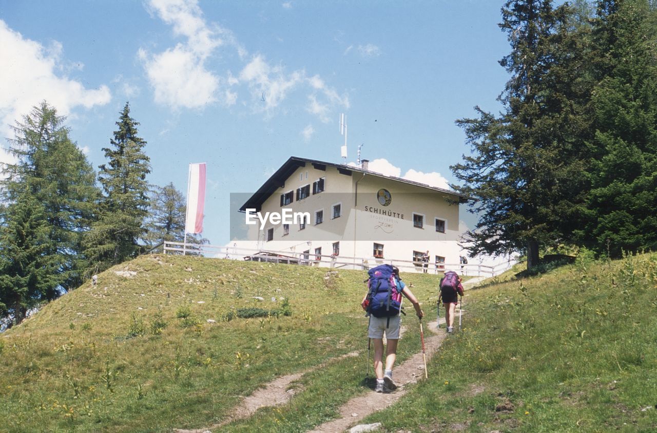 REAR VIEW OF MAN AND WOMAN WALKING ON BUILDING