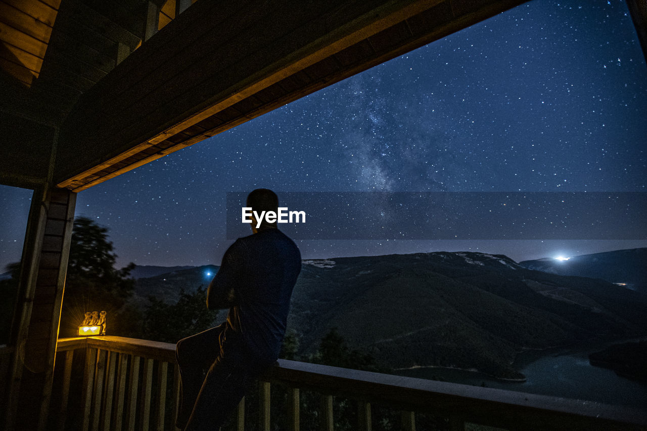 Rear view of man looking at sky at night