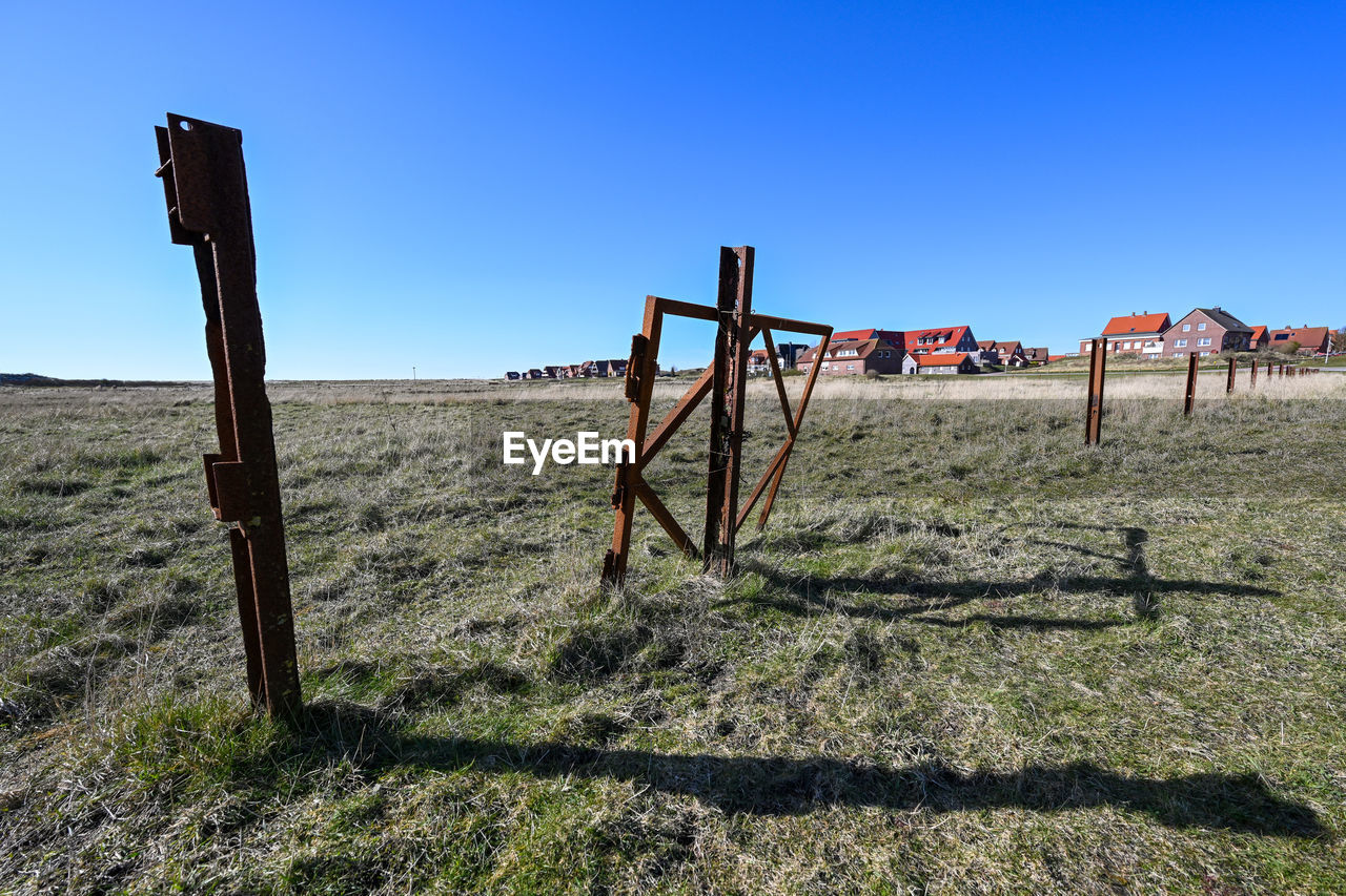 WOODEN FENCE ON FIELD AGAINST CLEAR BLUE SKY