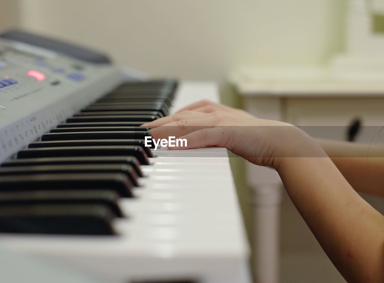 Cropped hands of girl playing piano