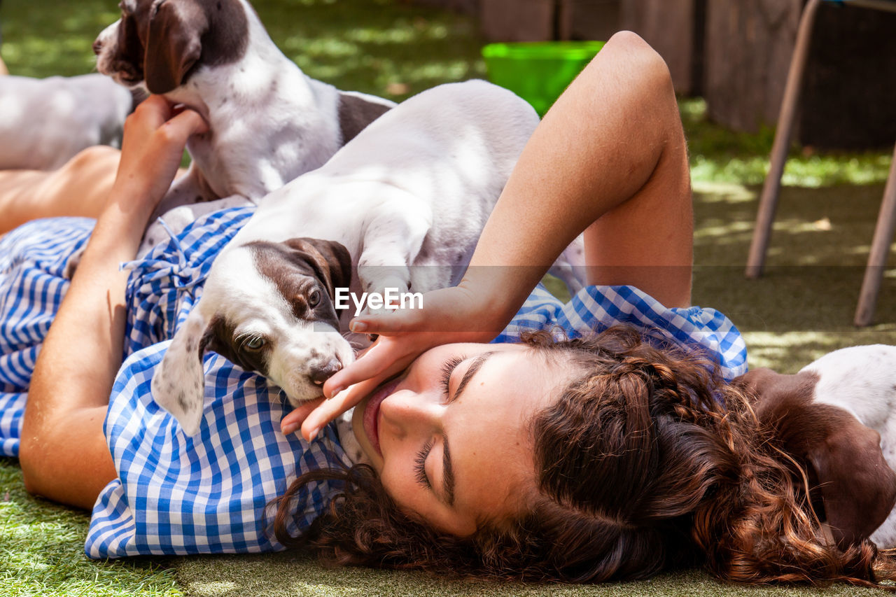 Beautiful young girl having fun with her small french braque puppies