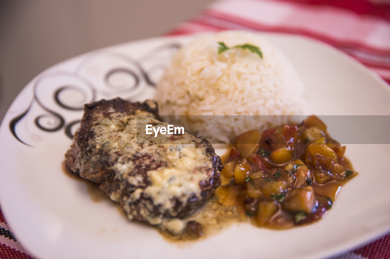 High angle view of fillet mignon with gorgonzola and rice in plate
