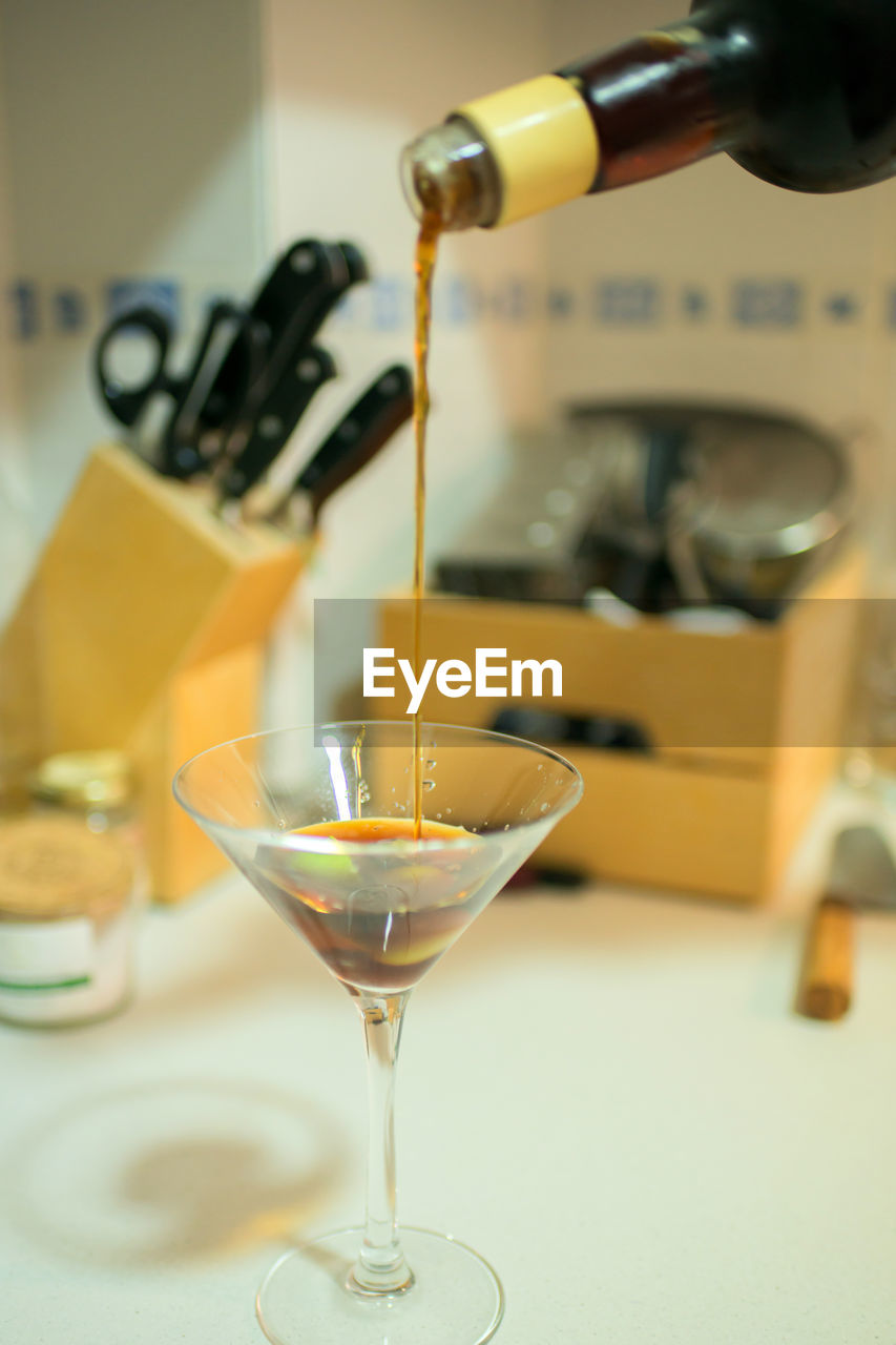 Pouring a martini glass in a domestic kitchen. glass cup