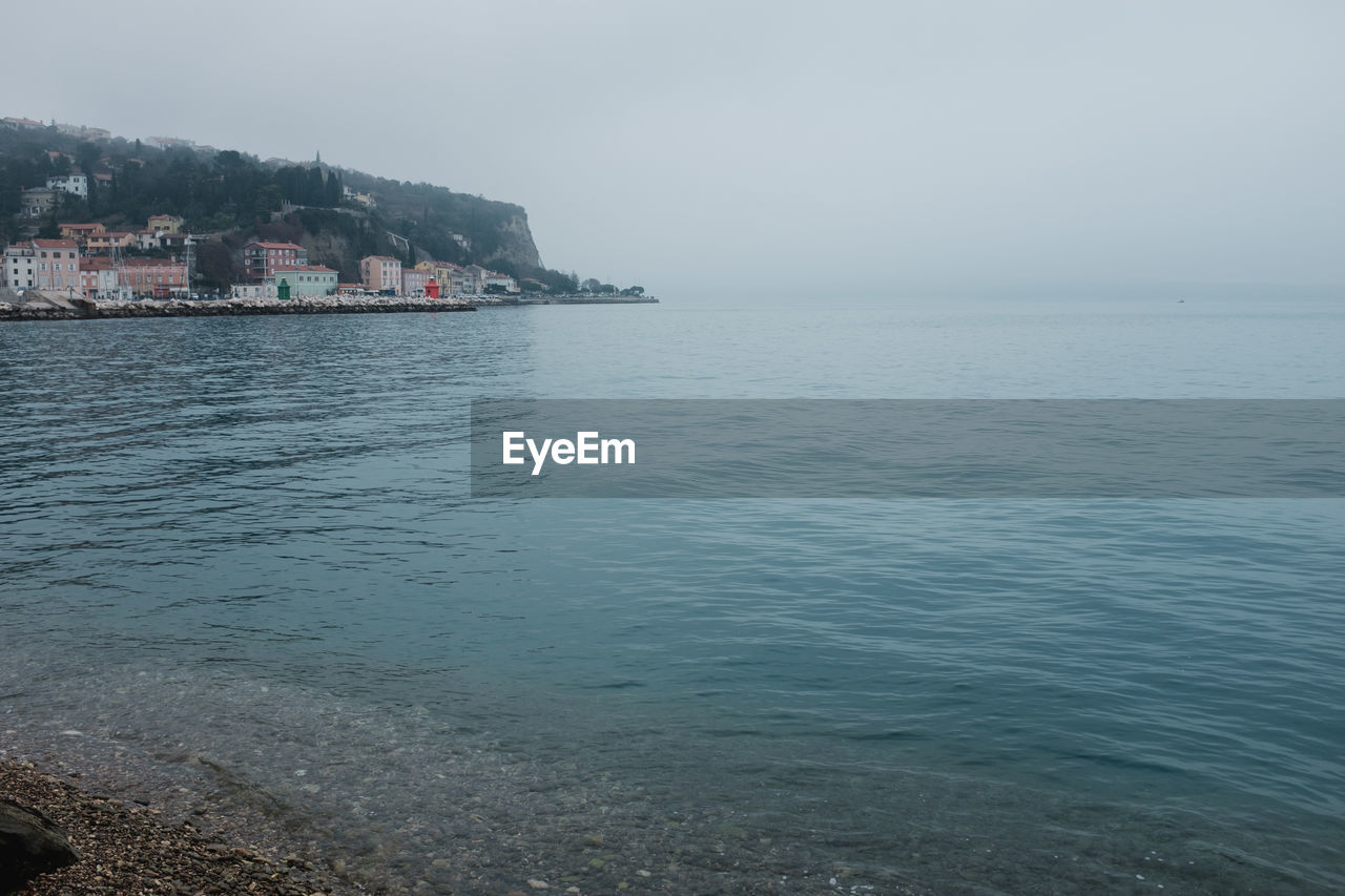 Scenic view of sea by city against clear sky