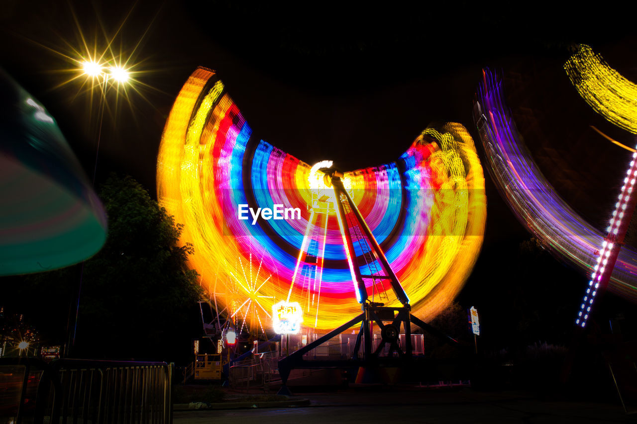 LOW ANGLE VIEW OF ILLUMINATED FIREWORKS AGAINST SKY AT NIGHT