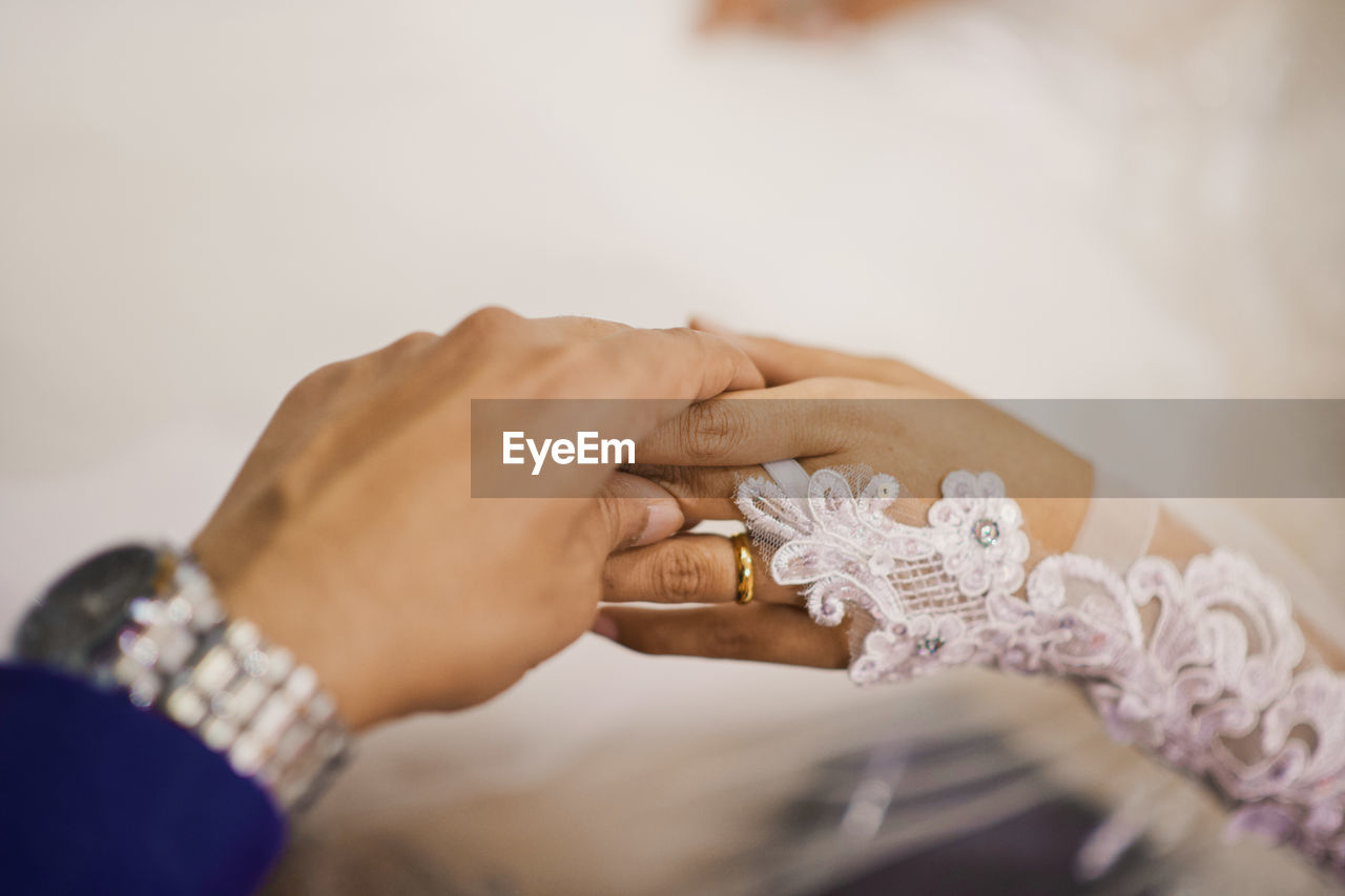 Cropped hand of bride holding wedding dress