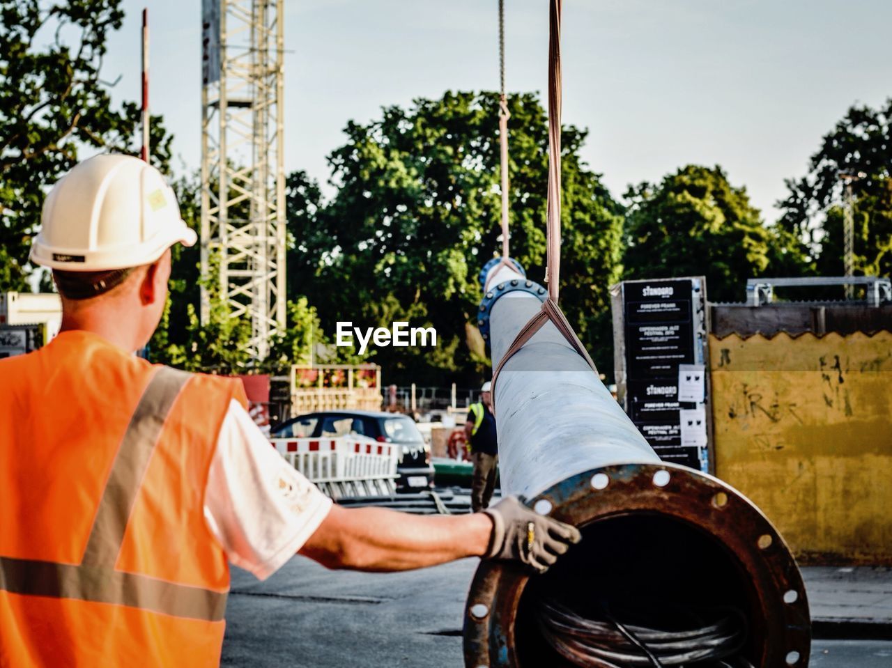 Pipe hanging on crane while worker at construction site