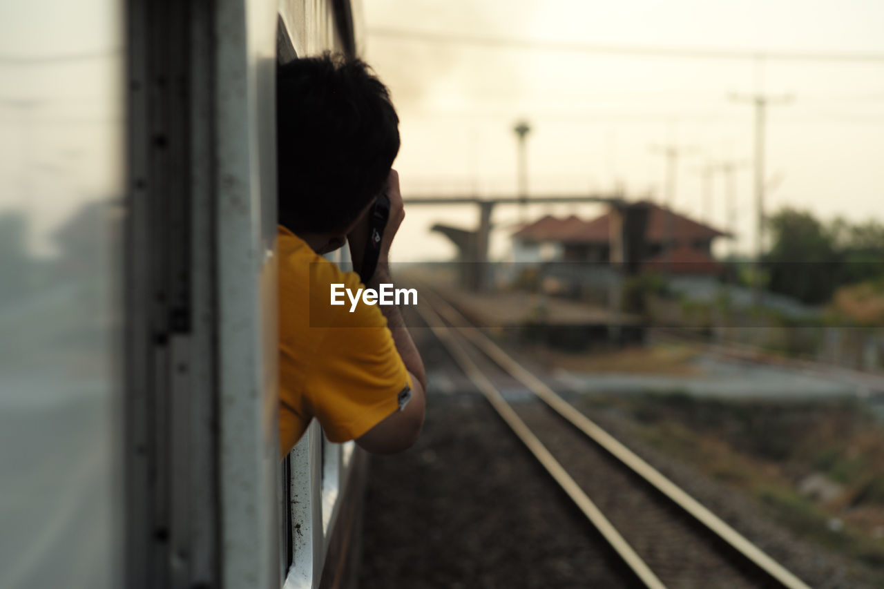 Rear view of man looking through train window