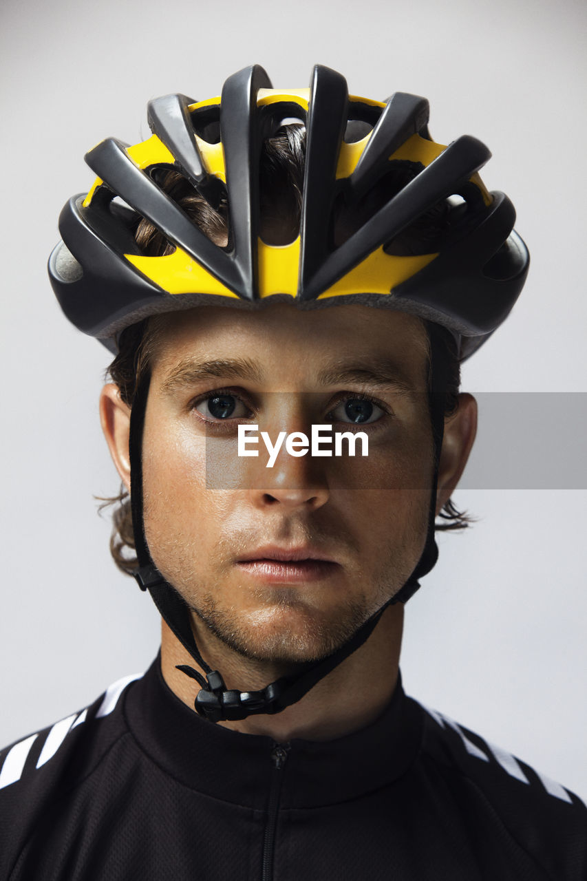 Portrait of confident cyclist wearing helmet against white background