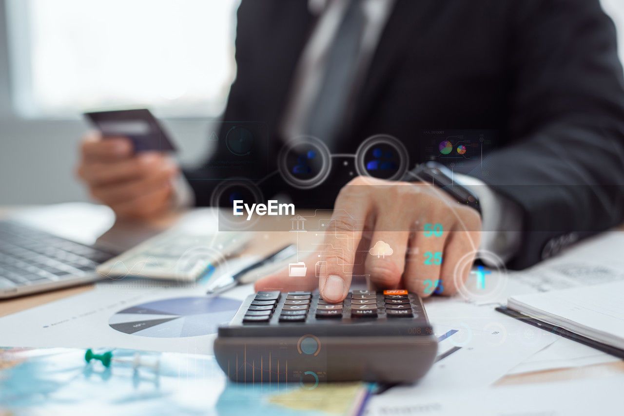 business, technology, adult, wireless technology, businessman, one person, computer, communication, business finance and industry, table, men, hand, office, furniture, desk, indoors, working, occupation, finance, writing, corporate business, using computer, internet, professional occupation, selective focus, laptop, computer network, smartphone, sitting, businesswear, document, portable information device, finance and economy, computer equipment, mobile phone, using laptop, portability, planning, place of work, digital tablet, person, formal wear, white-collar worker, close-up
