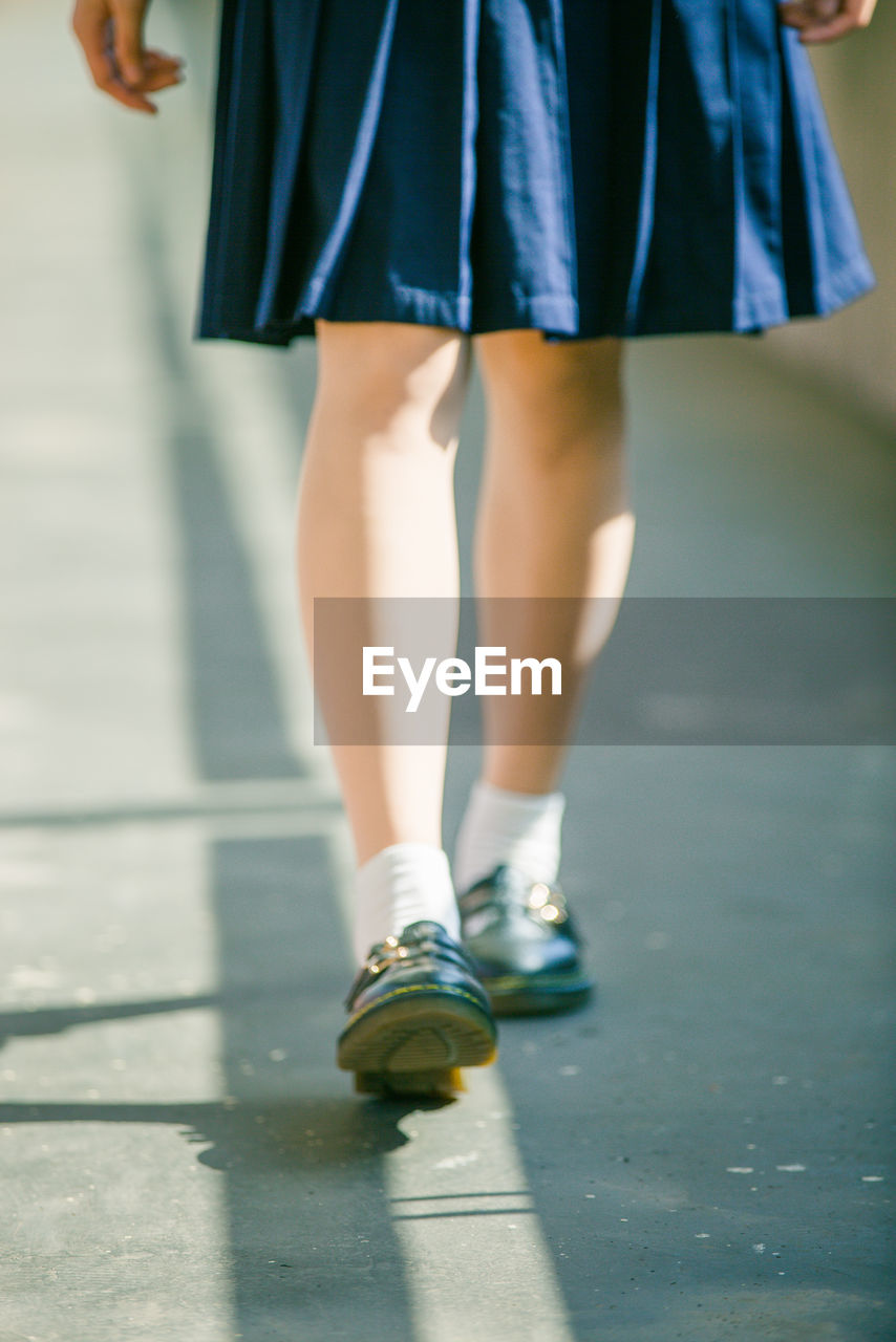 Low section of schoolgirl walking in corridor