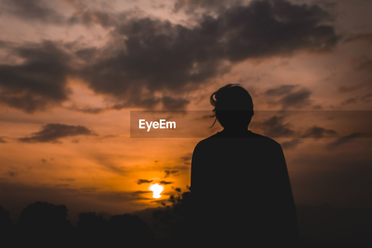 Silhouette man standing against orange sky