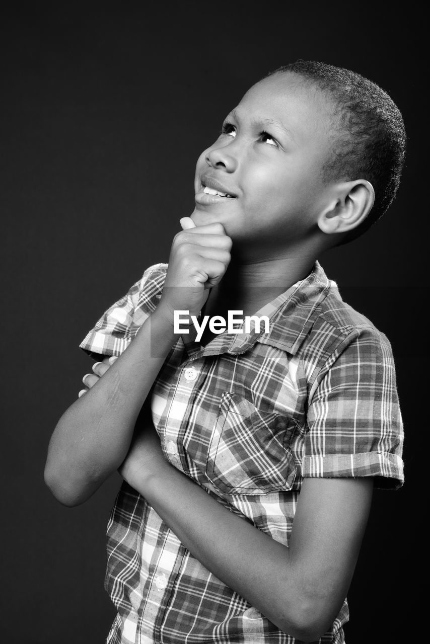 Side view of boy looking away against black background