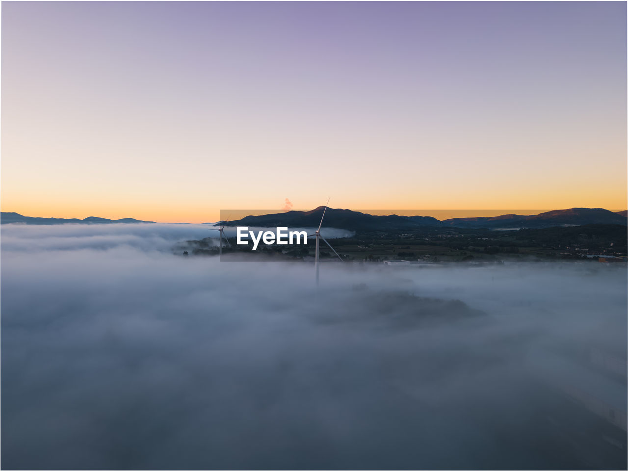 Panoramic view of wind farms in heavy fog in the morning during the rising sun