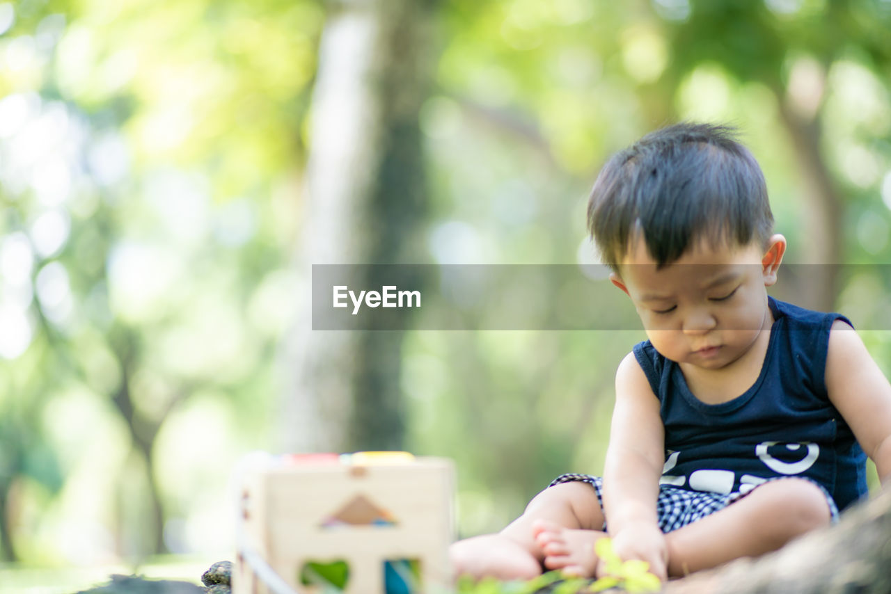 Boy looking away while sitting outdoors