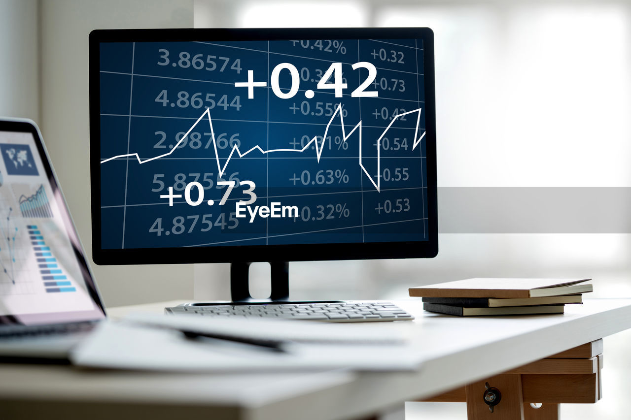 Stock market data on computer screen at office desk