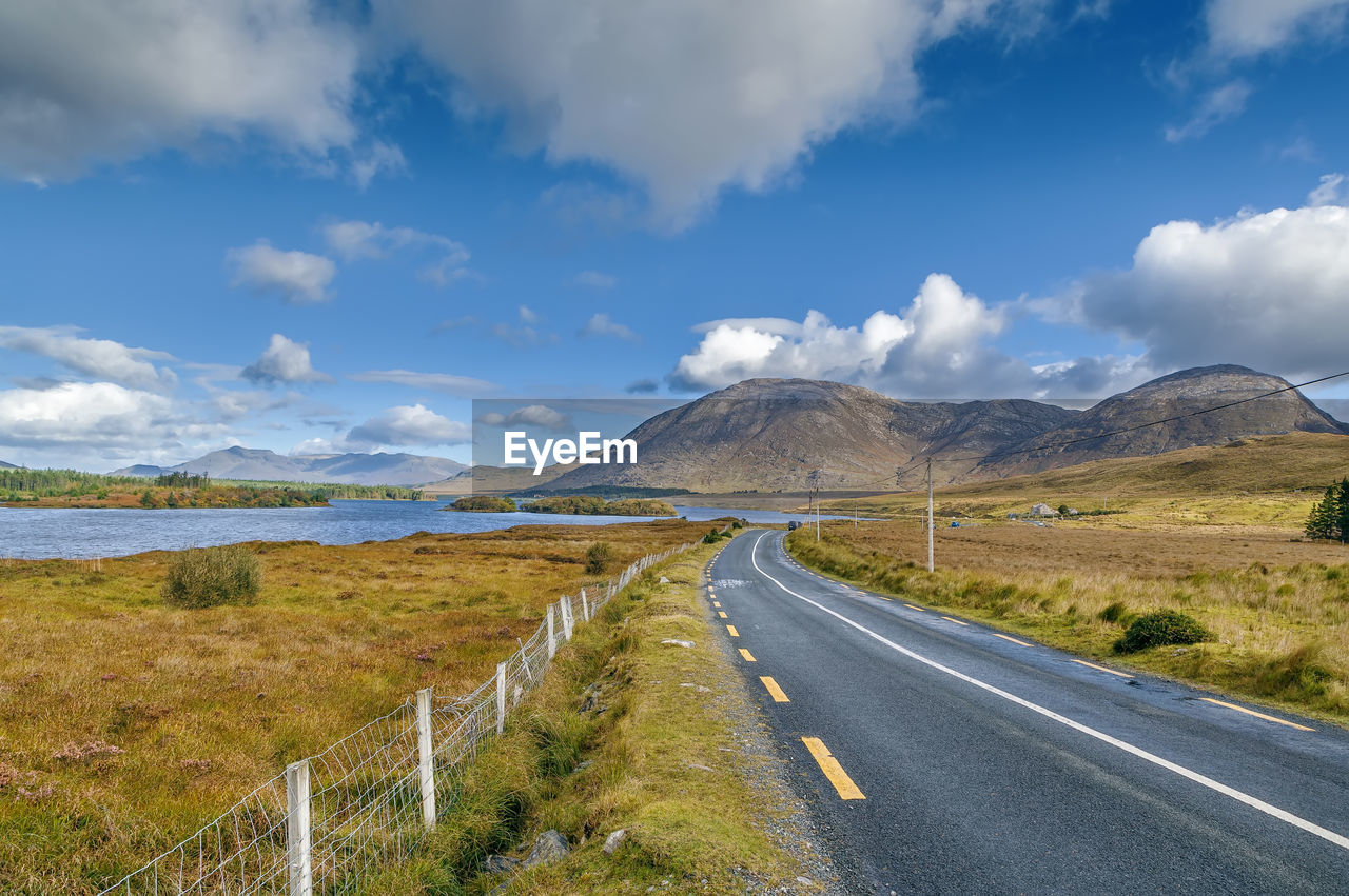 Road leading towards mountains against sky