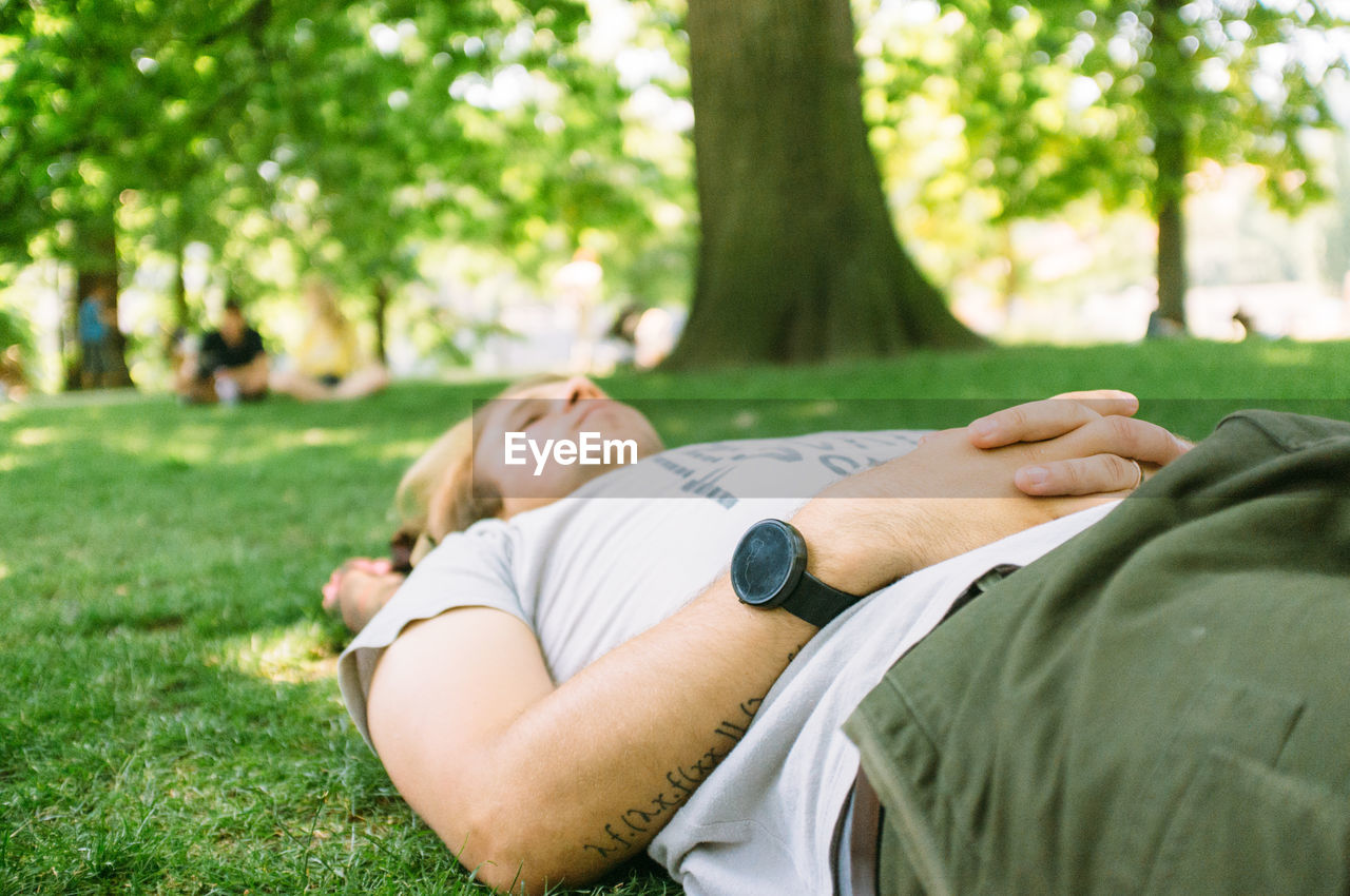 Mid adult man lying on grass in park