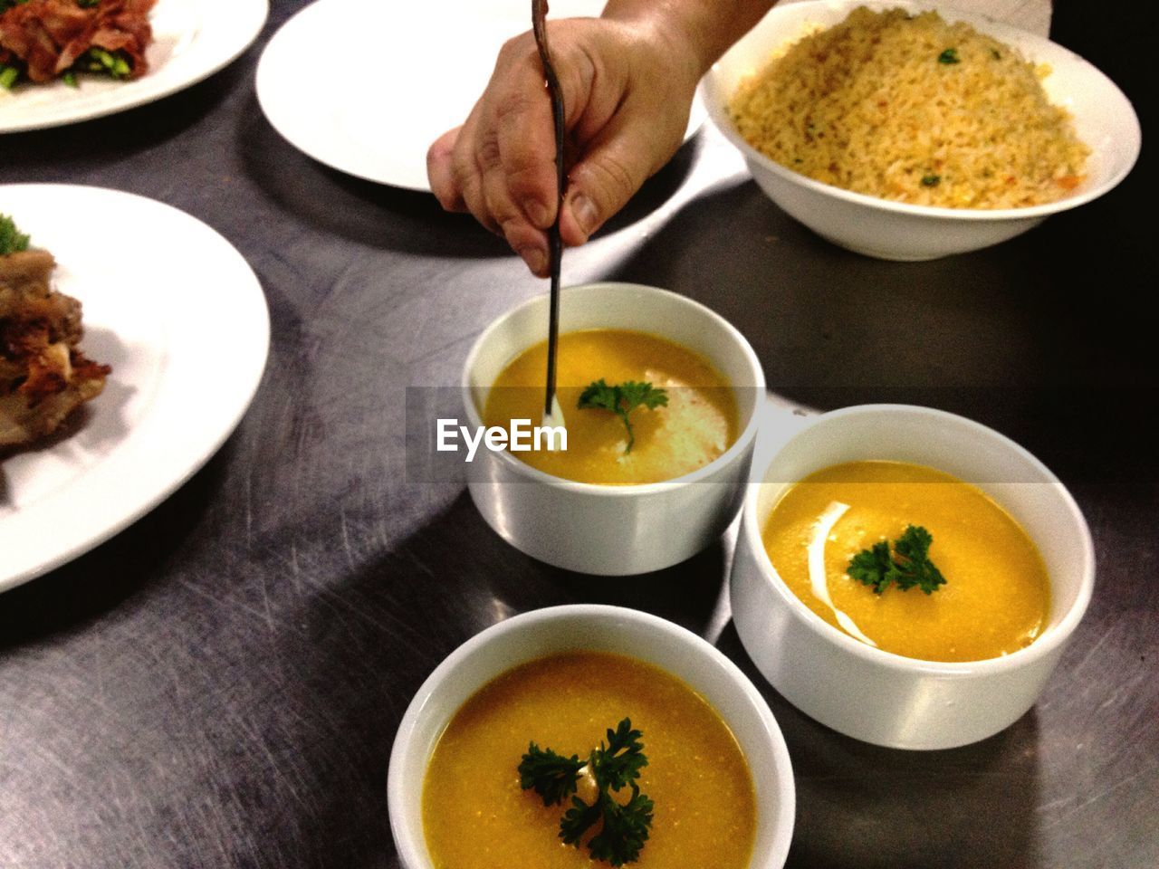 Cropped image of chef garnishing squash soup at restaurant