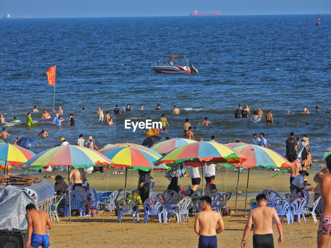 water, crowd, sea, large group of people, beach, group of people, umbrella, land, parasol, nature, sky, vacation, trip, leisure activity, beach umbrella, holiday, men, horizon over water, horizon, summer, adult, women, lifestyles, protection, body of water, sand, day, sunshade, travel destinations, enjoyment, relaxation, shade, travel, scenics - nature, outdoors, weekend activities, beauty in nature, mixed age range, clear sky, security, person, fun, tourism, sunlight, sunny, coast