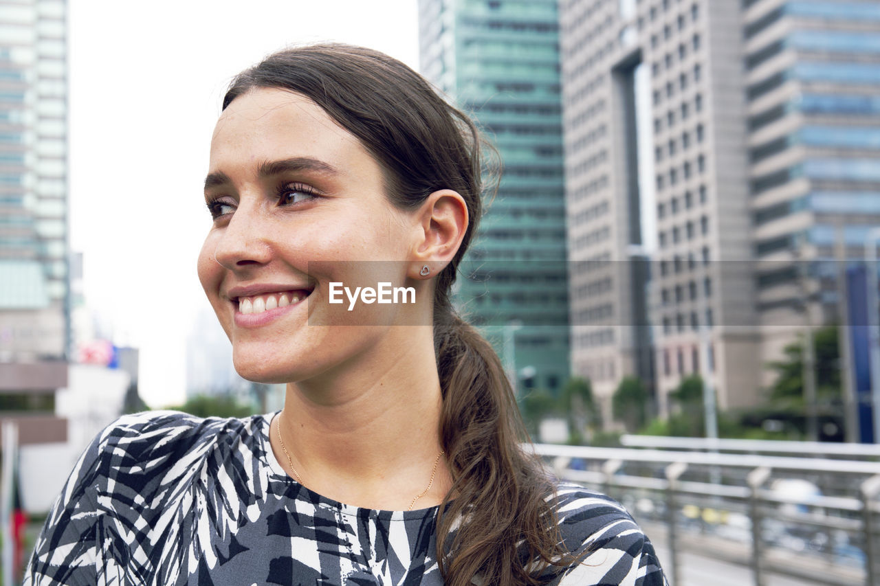 Smiling young woman looking away in city