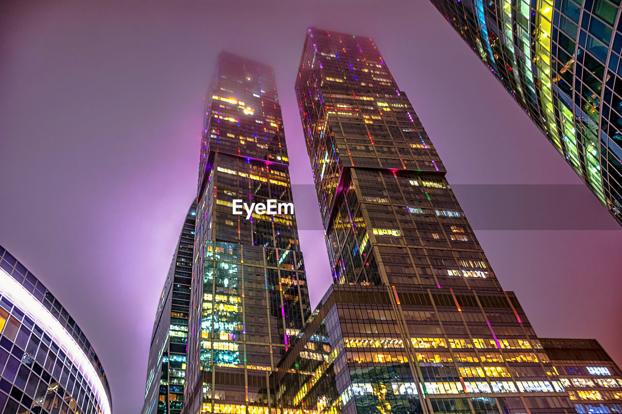 Low angle view of illuminated buildings against sky at night