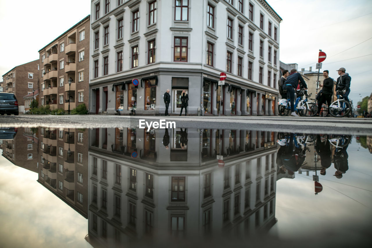 REFLECTION OF PEOPLE ON PUDDLE IN WATER