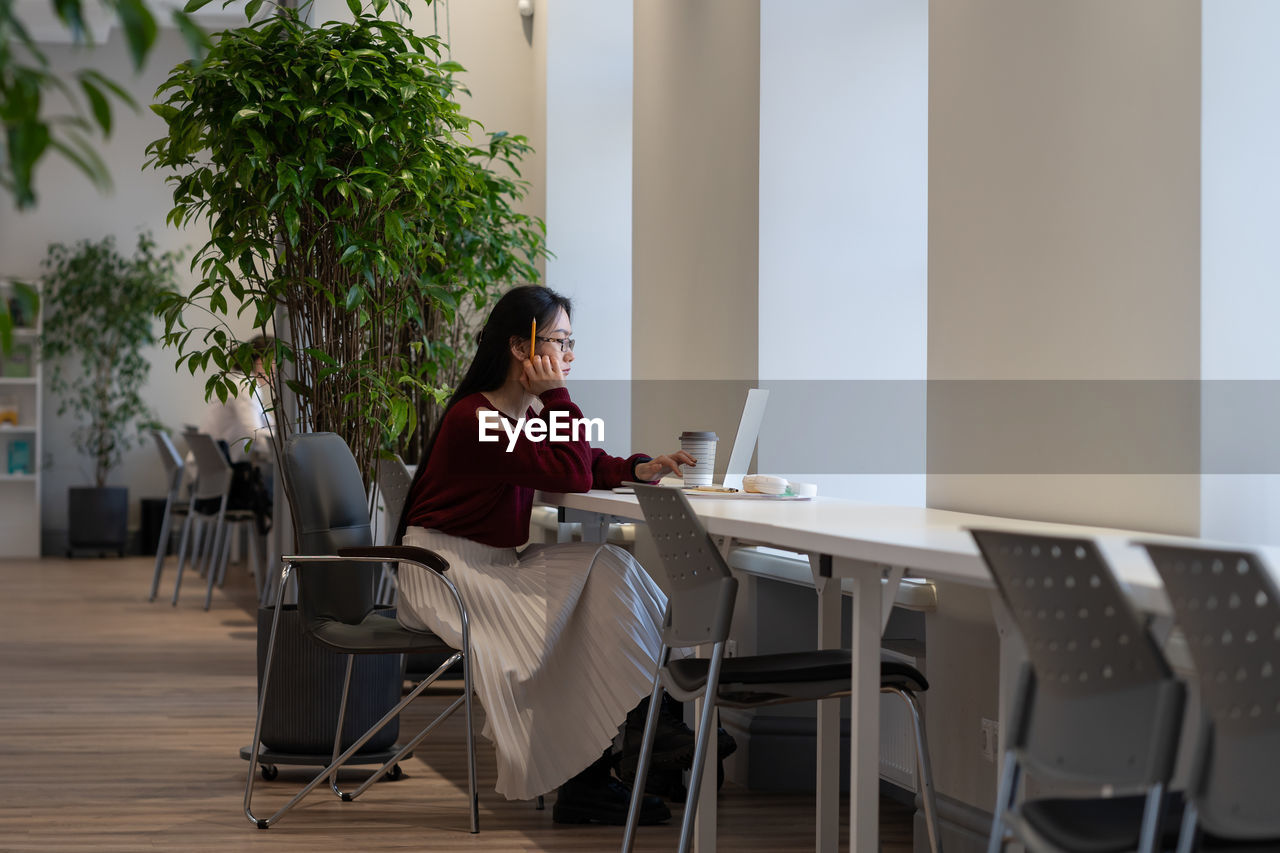 Young asian woman working remotely in modern public library, japanese female student studying online