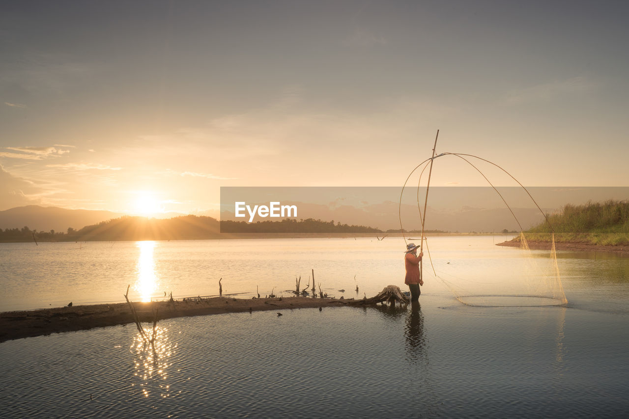 Fisherman against sky during sunset