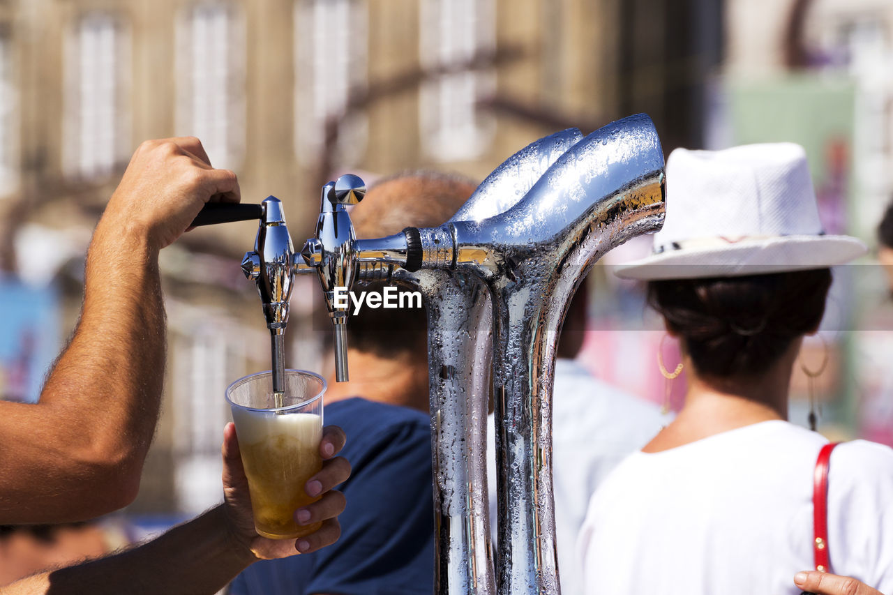Barman serving draft beer pouring in street fest with people on background