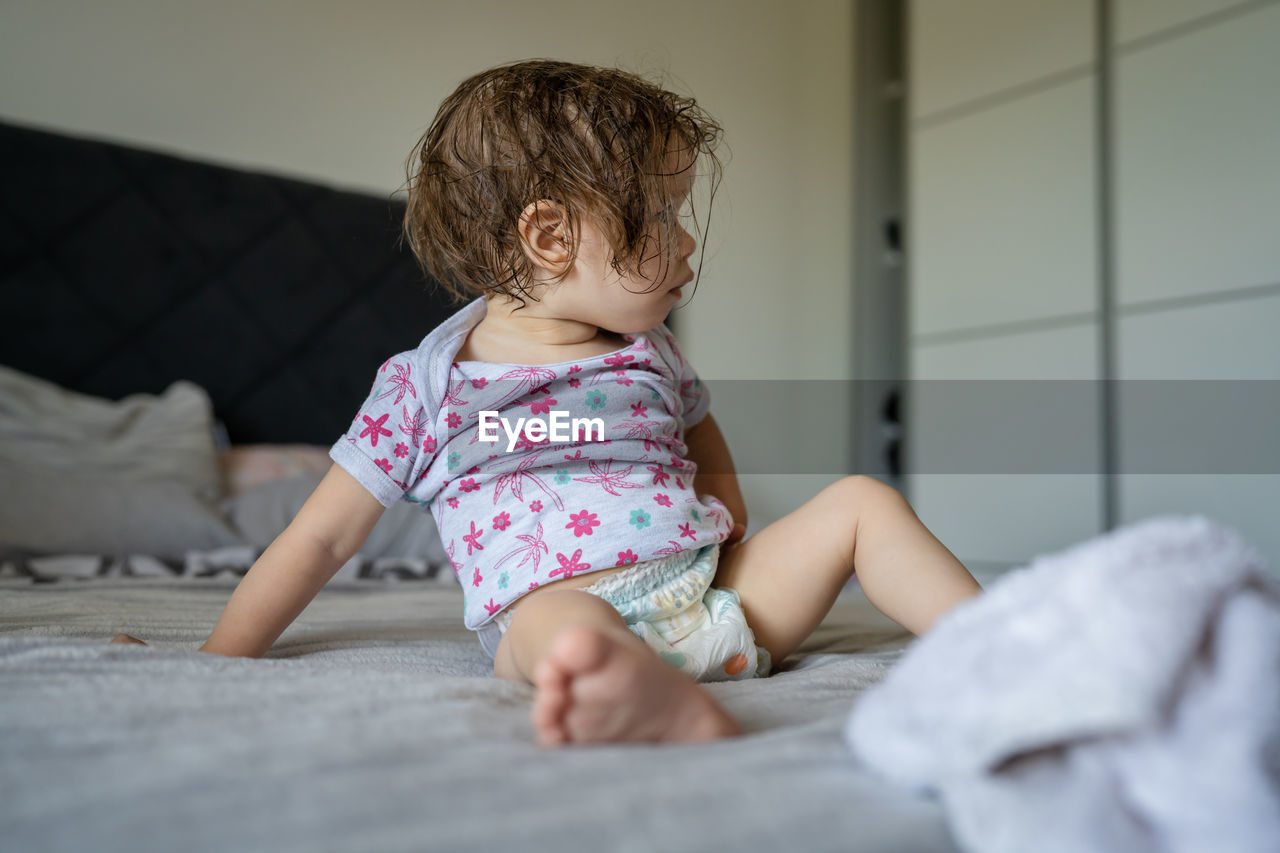 portrait of cute girl sitting on bed at home