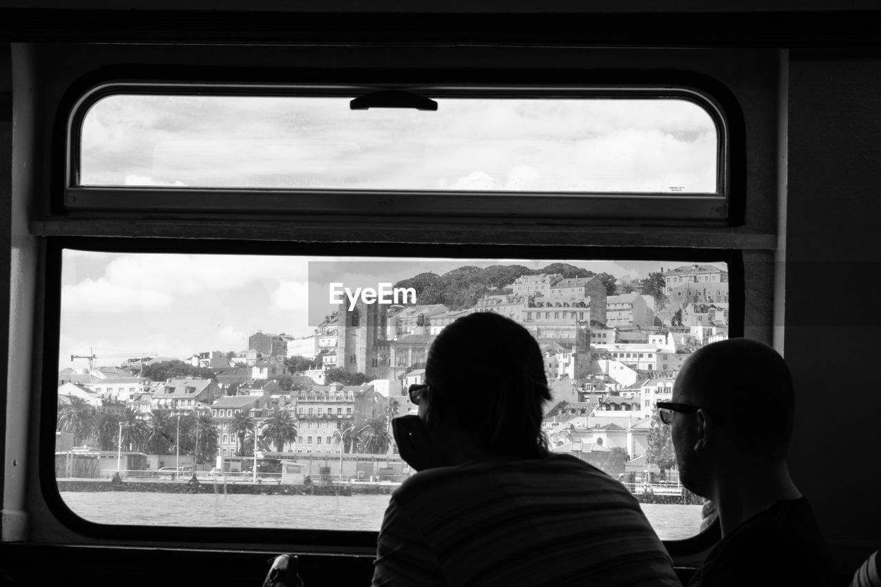 Rear view of friends viewing city through ferry boat