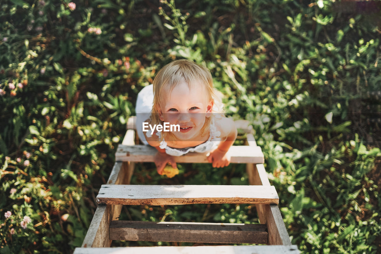 Portrait of cute smiling girl standing on ladder